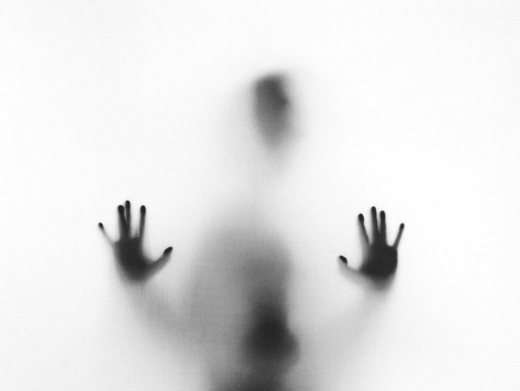 A silhouette of a person pressing their hands against glass