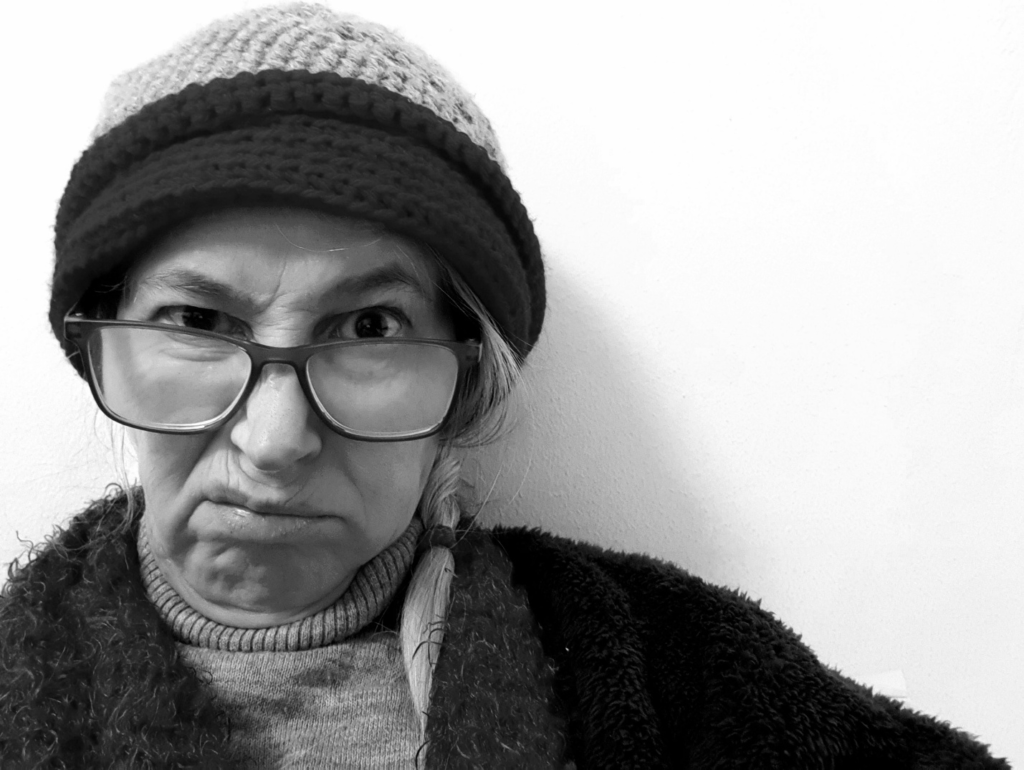 A grumpy old woman wearing a hat and glasses