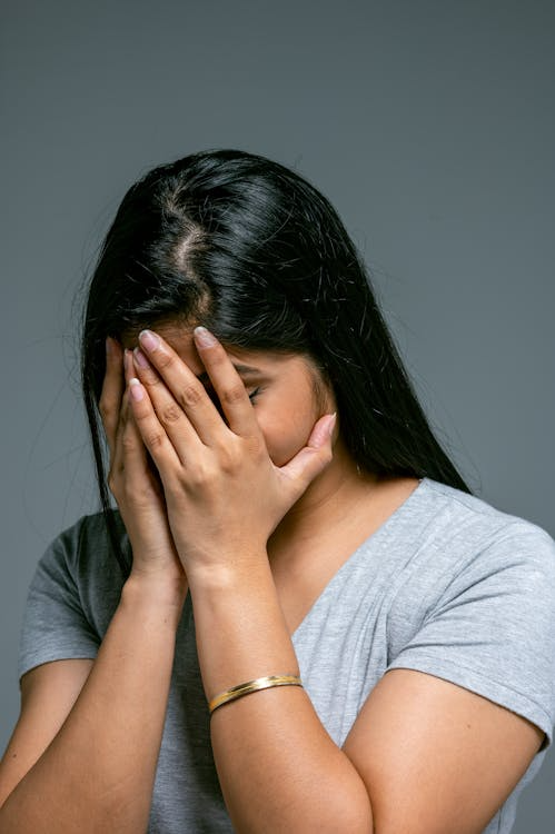 An image of a woman covering her face with her hands