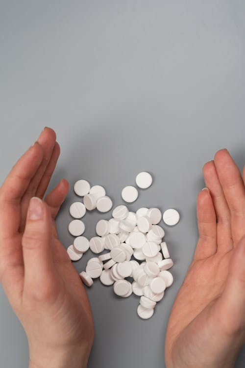 An image of white pills in between a person’s hands