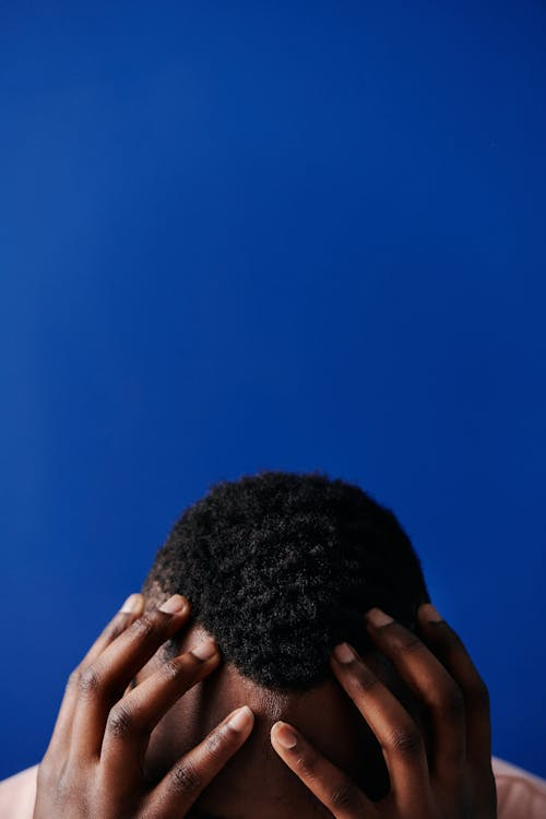 An image of a man with his hands on his head
