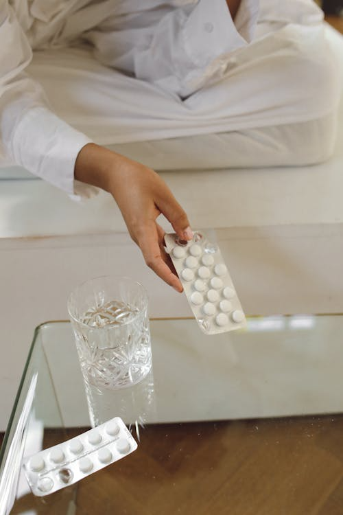 A person picking up a blister packet of medicine
