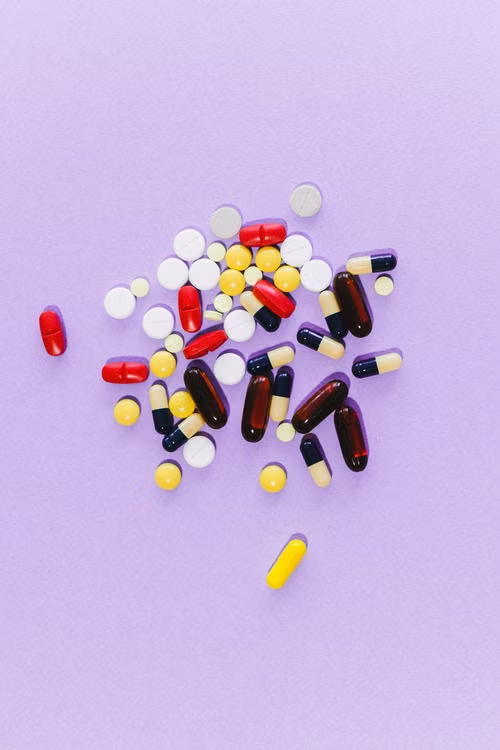 Assorted colorful pills and capsules on a purple surface