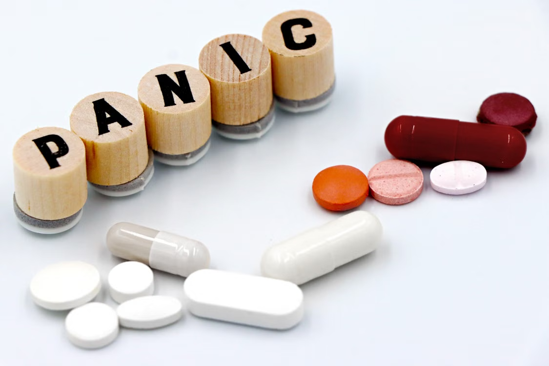 Assorted pills arranged beside wooden tiles spelling panic 