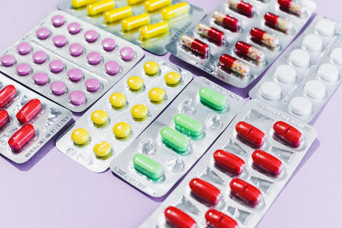A variety of pills in blister packs displayed on a wooden surface.