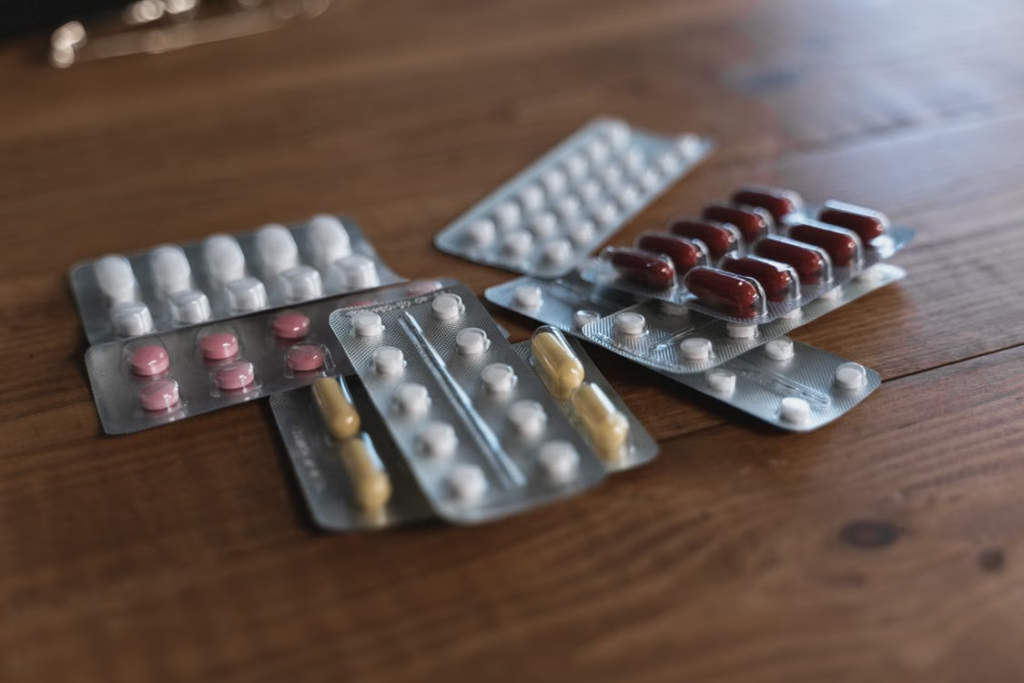 A variety of pills in blister packs displayed on a wooden surface.
