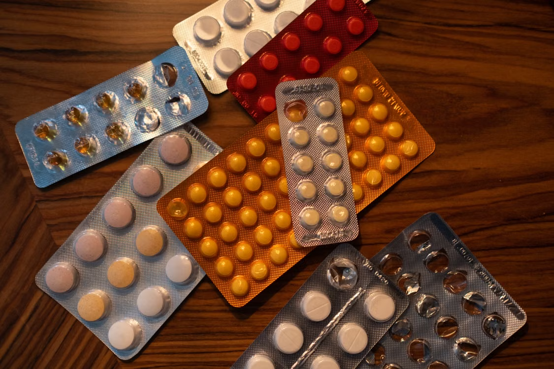 Colorful blister packs of medicine pills on a wooden surface.