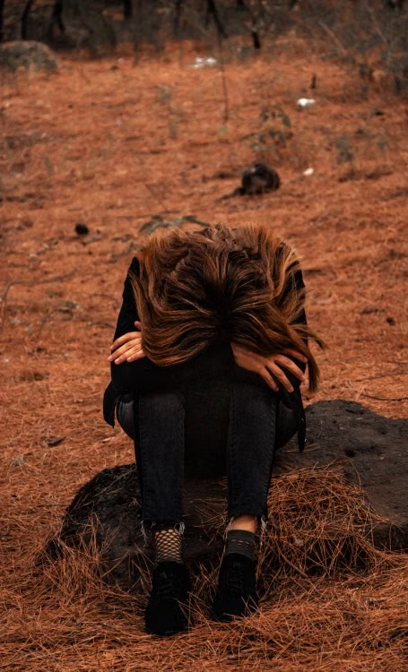 A person sitting alone on a rock against fall imagery.