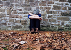 A person hiding their face and sitting on the ground